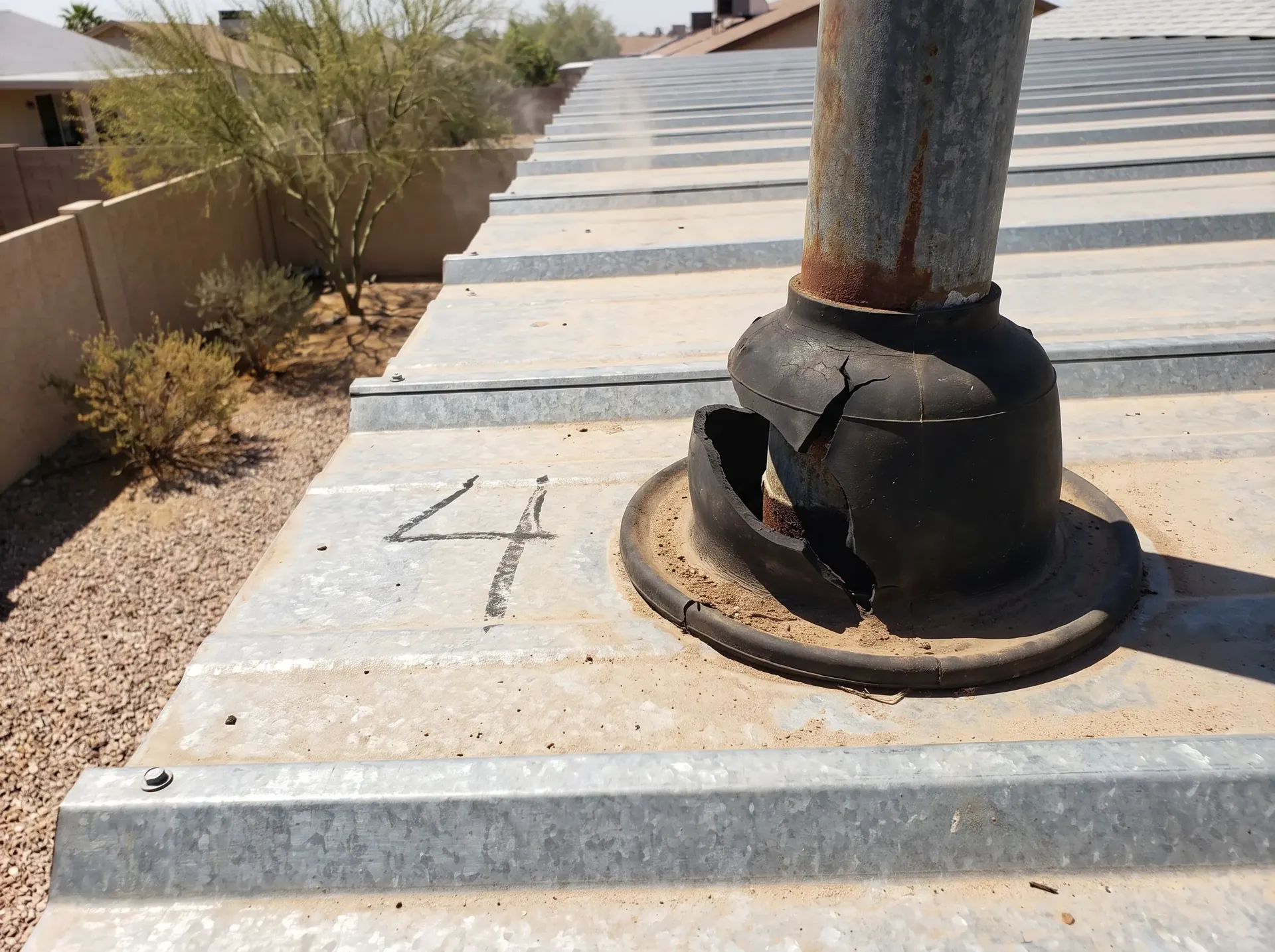 Chalk mark beside a failed pipe boot on a metal roof panel