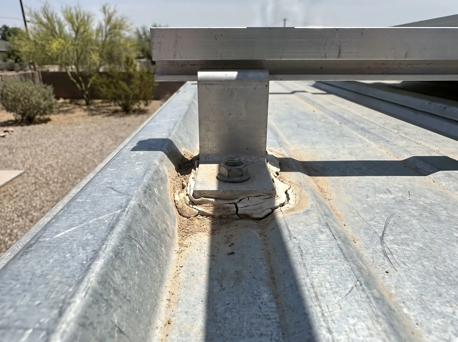 Solar mounting foot penetrating a metal roof panel with failed sealant
